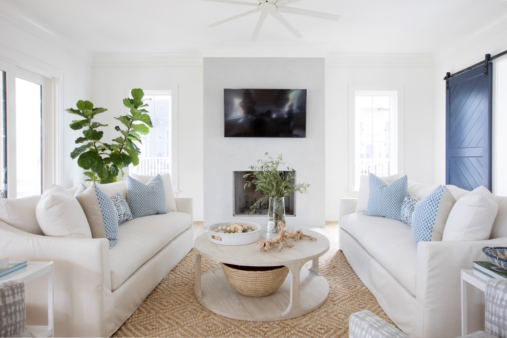 На фото: гостиная комната в морском стиле с белыми стенами, светлым паркетным полом, стандартным камином, телевизором на стене и бежевым полом с