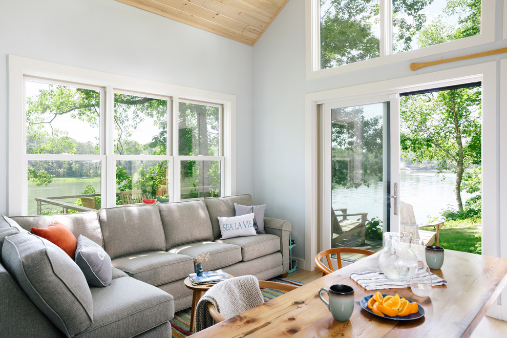 Diseño de salón abierto de estilo de casa de campo pequeño sin chimenea y televisor con paredes azules, suelo de madera clara y suelo beige