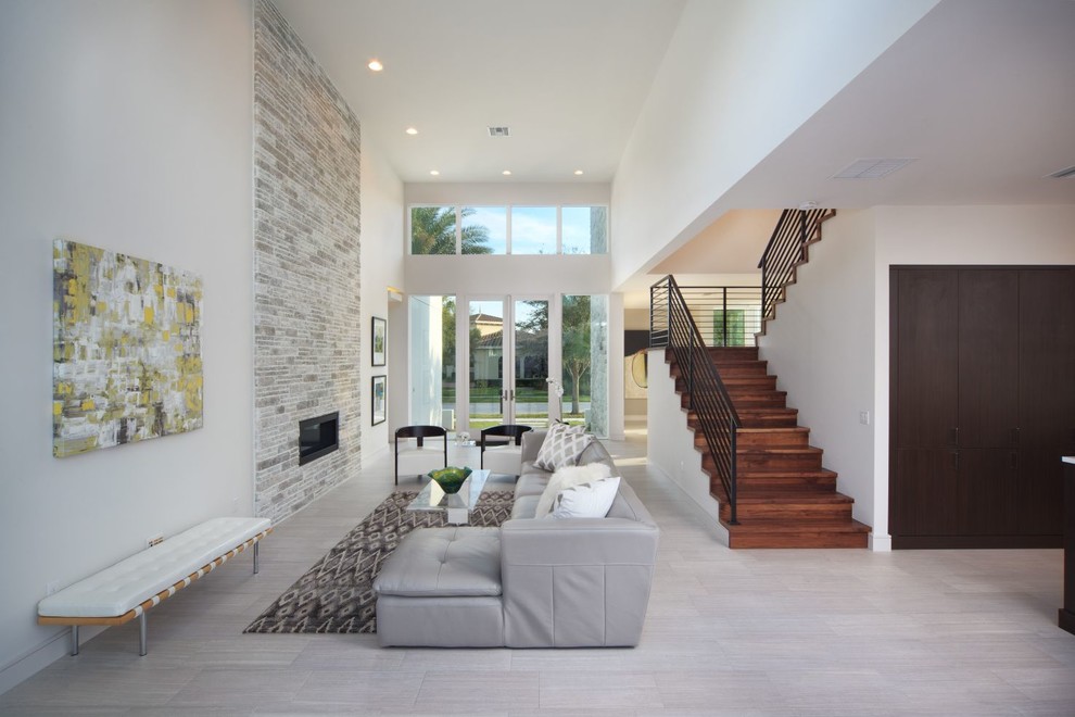 Offenes Modernes Wohnzimmer mit weißer Wandfarbe, Porzellan-Bodenfliesen, Gaskamin und Kaminumrandung aus Stein in Orlando