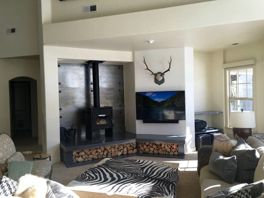 Foto de salón abierto moderno de tamaño medio con paredes blancas, estufa de leña, marco de chimenea de metal y televisor colgado en la pared