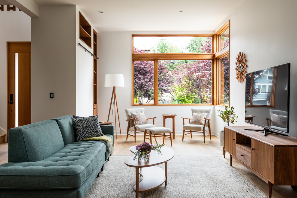 Mittelgroßes, Offenes Modernes Wohnzimmer mit weißer Wandfarbe, hellem Holzboden, freistehendem TV und beigem Boden in Seattle