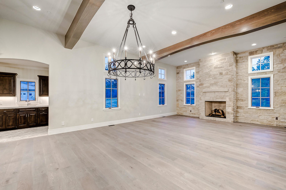 Photo of a large open plan living room in Denver with white walls, light hardwood flooring, a standard fireplace, a stone fireplace surround, no tv and brown floors.