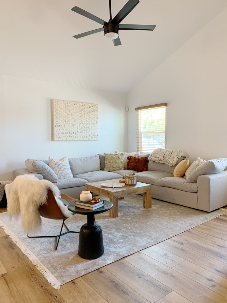 This is an example of a medium sized scandinavian open plan living room in Phoenix with white walls, medium hardwood flooring, a wall mounted tv, beige floors and a vaulted ceiling.
