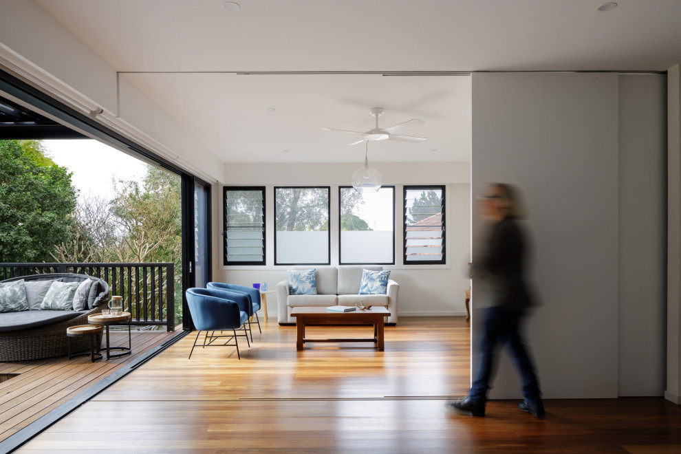 Esempio di un soggiorno design di medie dimensioni e chiuso con pareti bianche, parquet chiaro, TV a parete e pannellatura