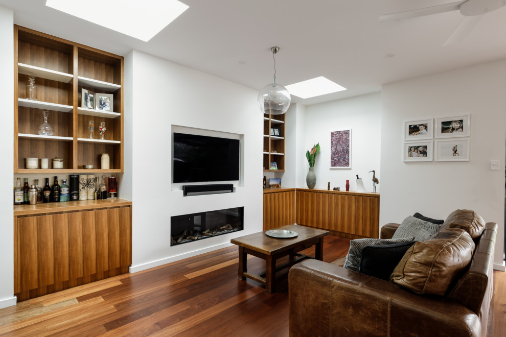Immagine di un soggiorno minimal di medie dimensioni e chiuso con pareti bianche, parquet chiaro, TV a parete, pavimento marrone e pannellatura