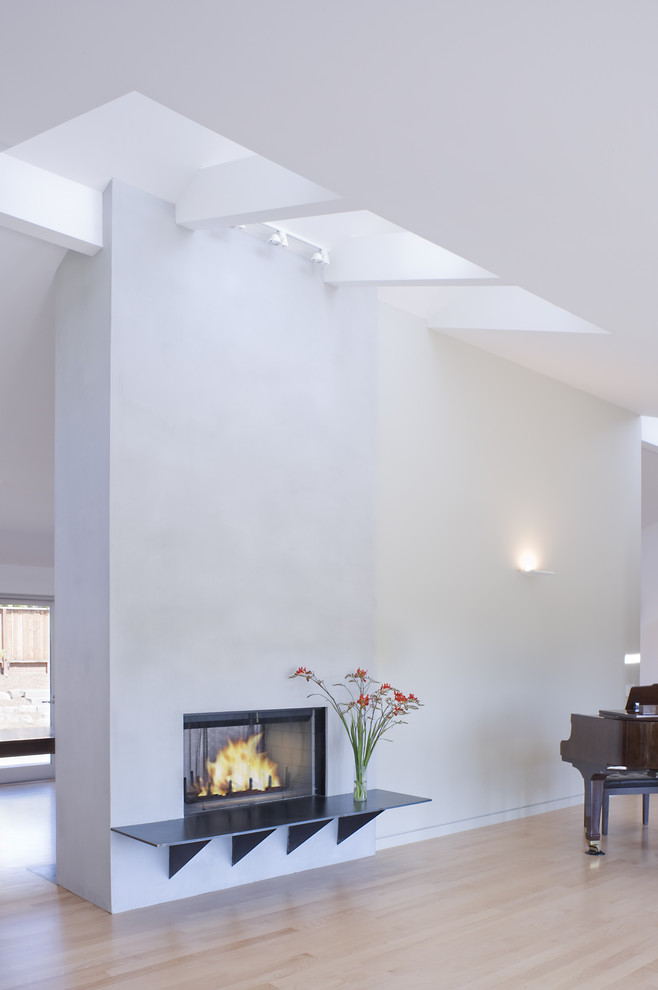 This is an example of a modern living room in San Francisco with white walls and a two-sided fireplace.