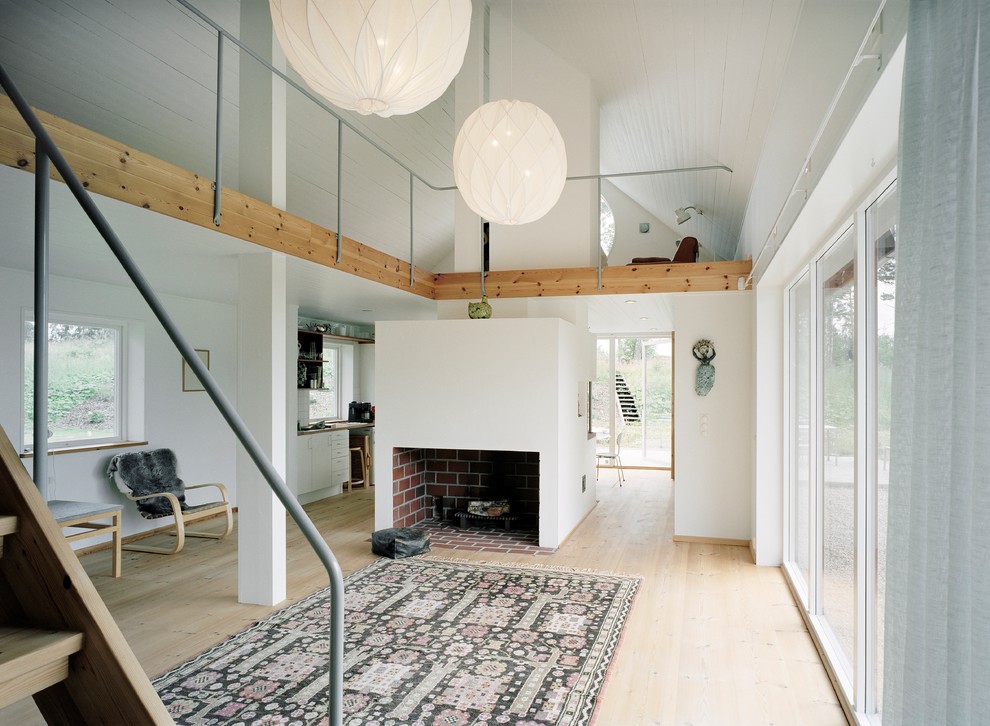 Inspiration for a large scandinavian open plan living room in Stockholm with white walls, light hardwood flooring, a standard fireplace and no tv.
