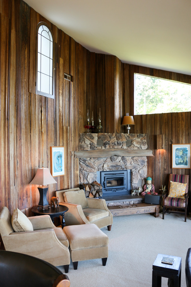 Photo of a large eclectic open plan living room in Seattle with a wood burning stove, a stone fireplace surround, brown walls, carpet, a freestanding tv, beige floors, a vaulted ceiling and panelled walls.
