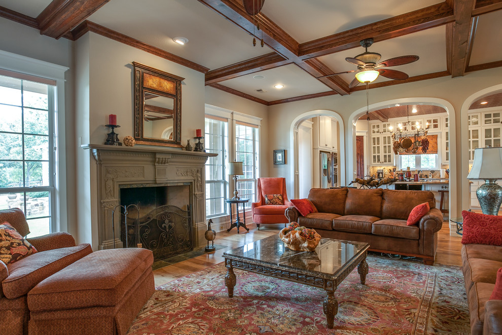 Großes, Offenes Klassisches Wohnzimmer mit beiger Wandfarbe, braunem Holzboden, Kamin, Kaminumrandung aus Stein und Multimediawand in Dallas
