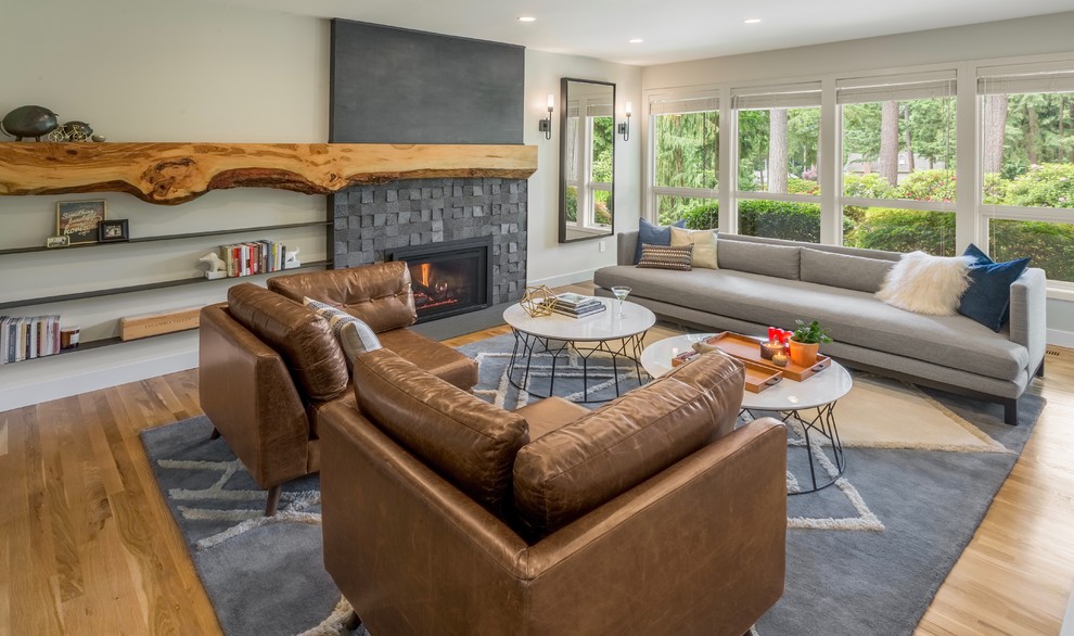 Mittelgroßes, Abgetrenntes Klassisches Wohnzimmer mit grauer Wandfarbe, braunem Holzboden, Kamin, Kaminumrandung aus Stein und braunem Boden in Seattle