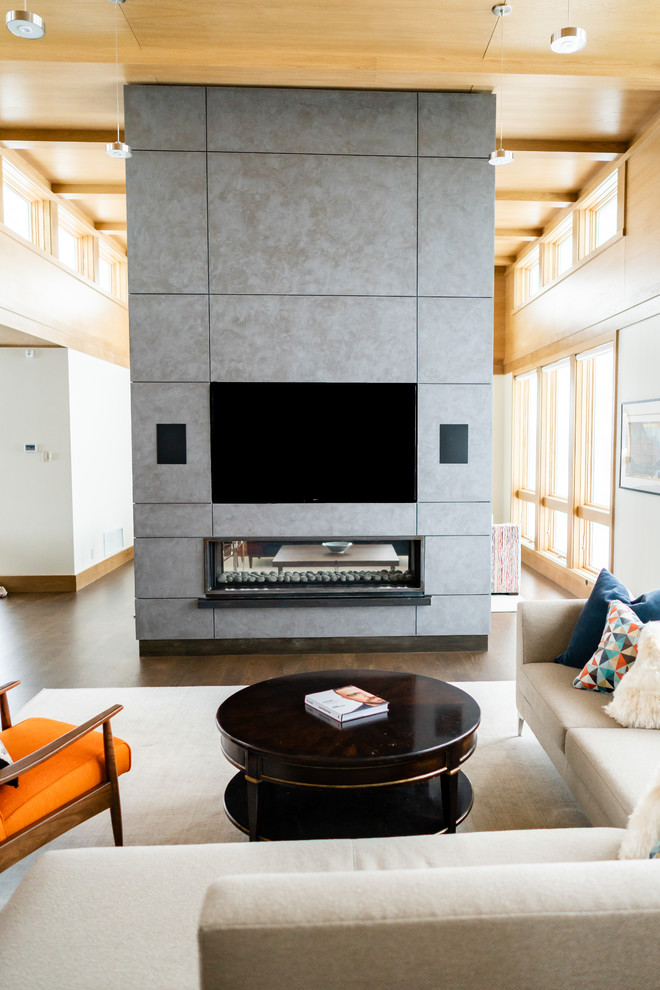 Photo of a large contemporary open plan living room in Minneapolis with a two-sided fireplace, a concrete fireplace surround, a built-in media unit, beige walls, medium hardwood flooring and brown floors.