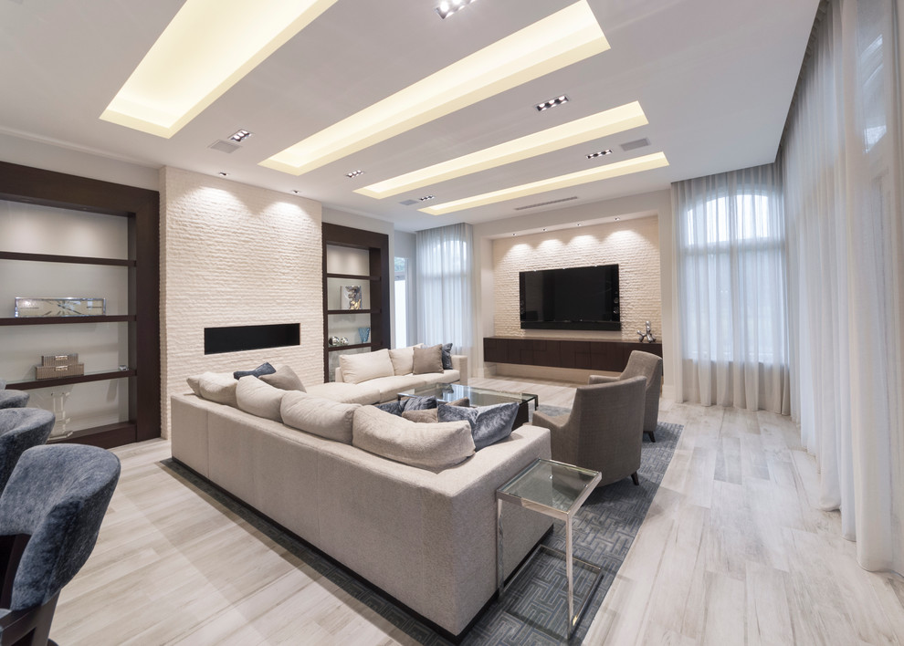 Стильный дизайн: большая открытая гостиная комната в стиле модернизм с белыми стенами, полом из керамогранита, фасадом камина из кирпича, телевизором на стене и бежевым полом без камина - последний тренд