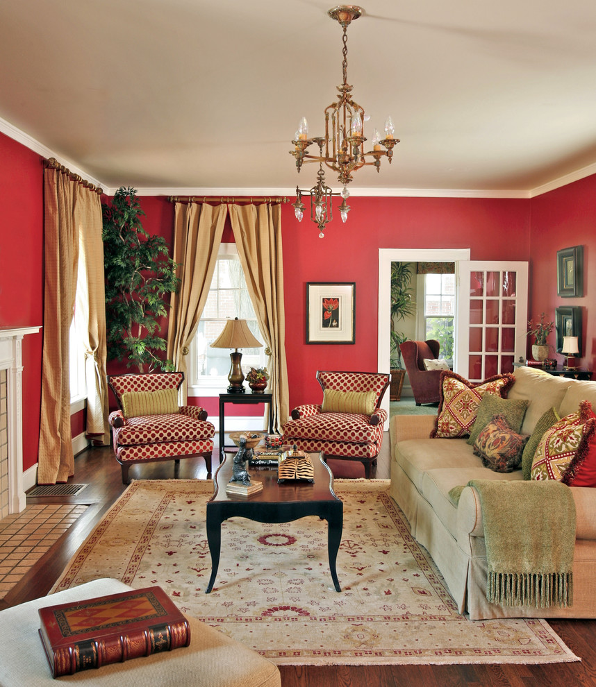 Cette photo montre un grand salon chic fermé avec un mur rouge, un sol en bois brun, une cheminée standard, un manteau de cheminée en pierre, un téléviseur fixé au mur et canapé noir.
