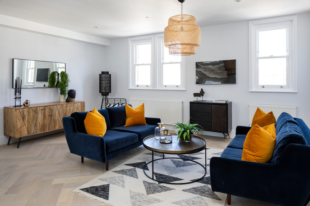 Cette image montre un salon design de taille moyenne avec un mur blanc, parquet clair, un téléviseur fixé au mur et un sol beige.