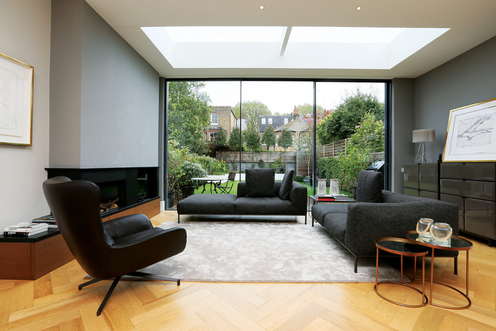 Repräsentatives, Abgetrenntes Modernes Wohnzimmer mit grauer Wandfarbe, hellem Holzboden, Gaskamin und Kaminumrandung aus Metall in London