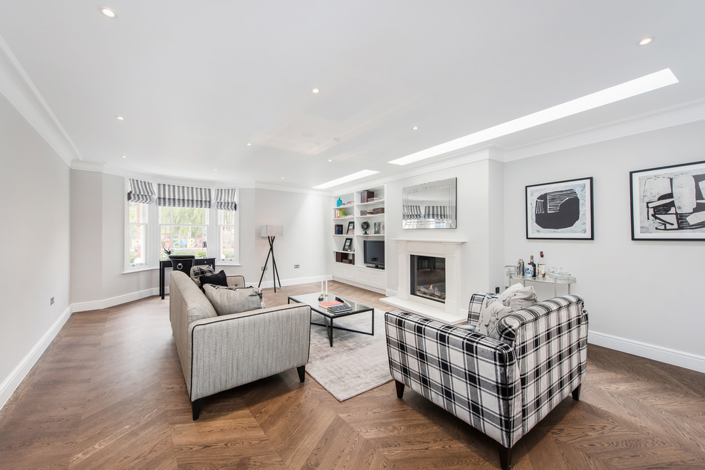 Photo of a large traditional formal enclosed living room in London with white walls, medium hardwood flooring, a standard fireplace, a wooden fireplace surround and a freestanding tv.