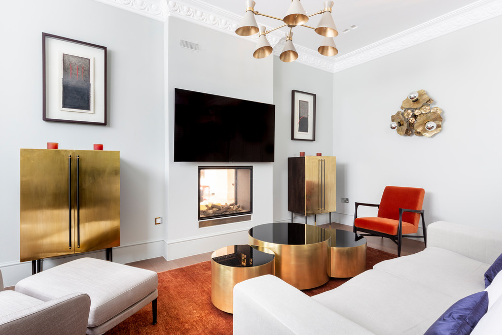 Ejemplo de salón actual con paredes grises, suelo de madera en tonos medios, chimenea de doble cara, televisor colgado en la pared y suelo marrón