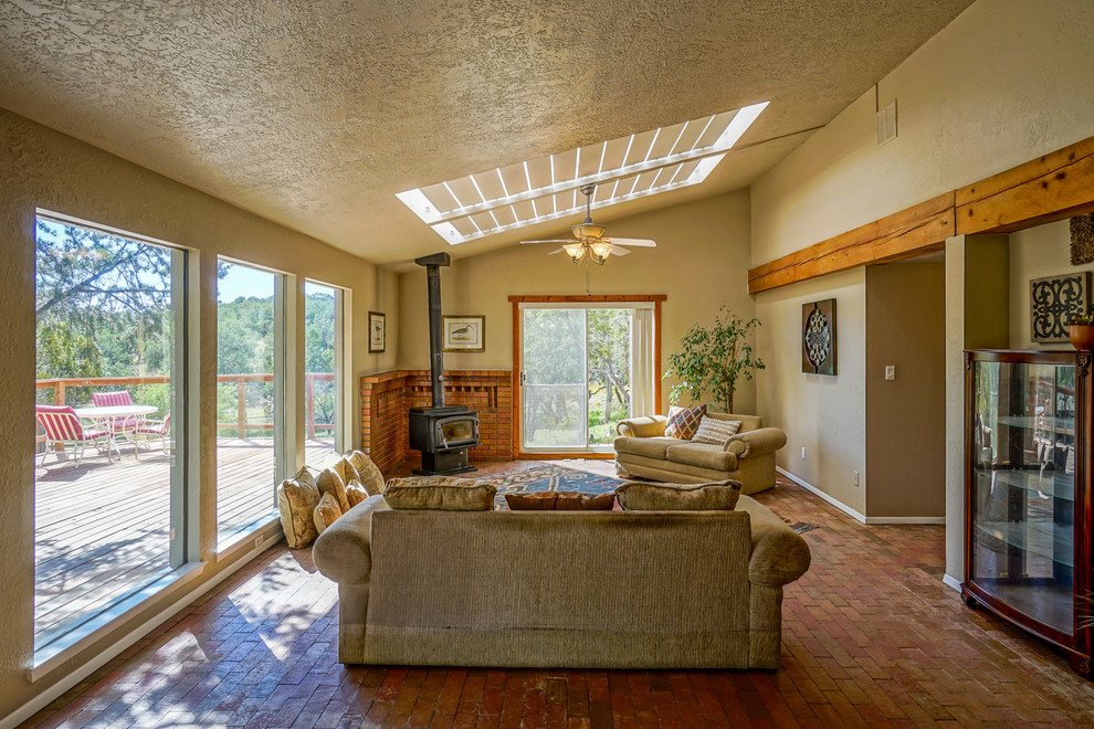 Immagine di un soggiorno american style chiuso con pareti beige, pavimento in mattoni, camino ad angolo e cornice del camino in metallo
