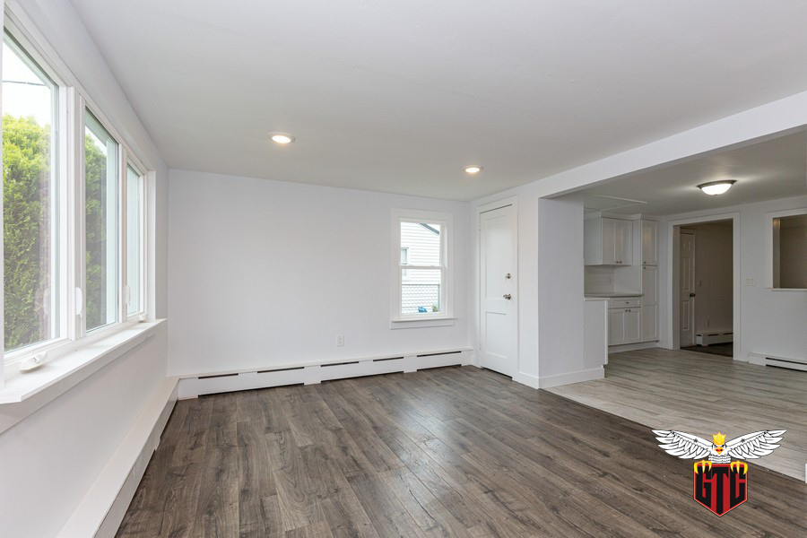 Cette image montre un salon minimaliste de taille moyenne avec un mur gris, sol en stratifié et un sol marron.