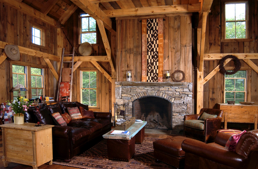 Imagen de biblioteca en casa abierta rural de tamaño medio con paredes marrones, suelo de madera en tonos medios, todas las chimeneas y marco de chimenea de piedra
