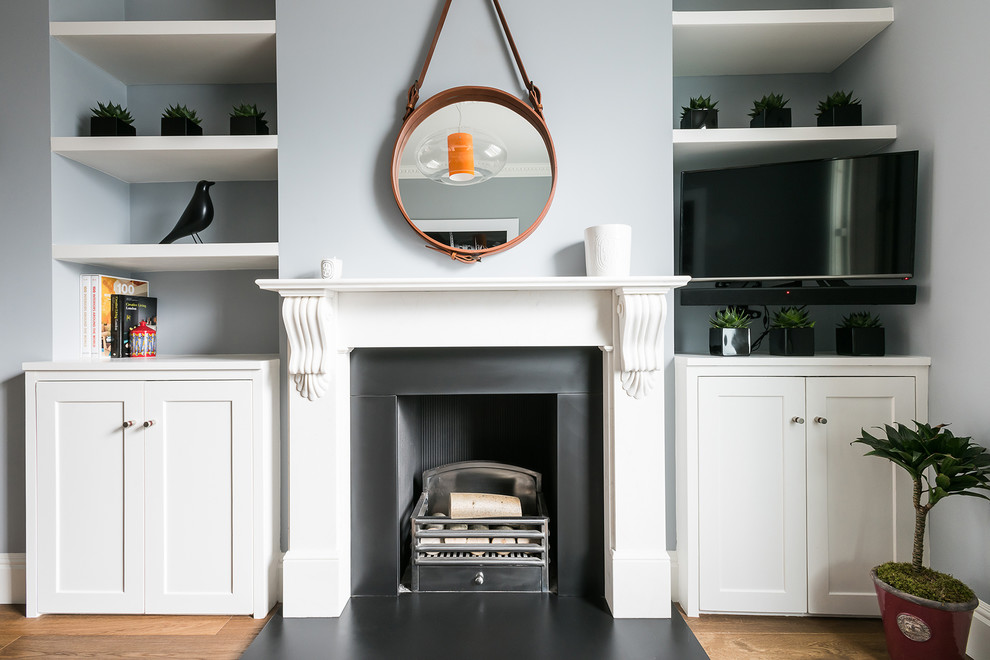 Foto de salón minimalista con paredes azules, suelo de madera en tonos medios, todas las chimeneas y televisor colgado en la pared