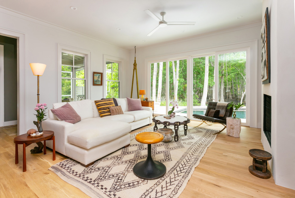 Cette image montre un grand salon minimaliste ouvert avec un mur blanc, parquet clair, une cheminée standard et un sol beige.