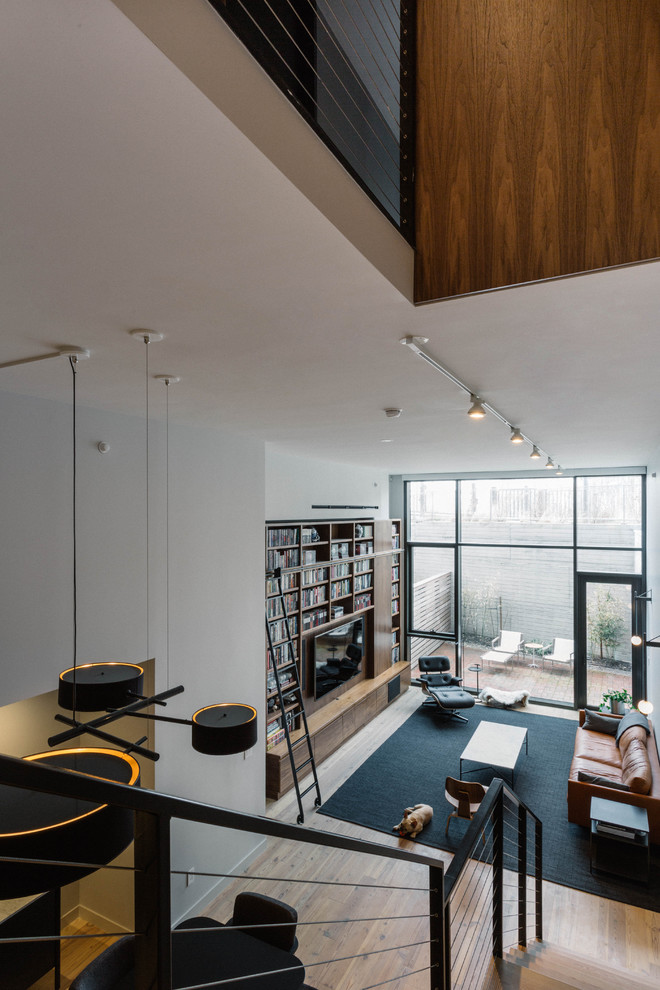 Immagine di un grande soggiorno design stile loft con libreria, pareti grigie, parquet chiaro, parete attrezzata e pavimento beige