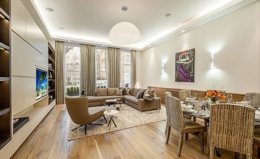 Modernes Wohnzimmer mit beiger Wandfarbe, braunem Holzboden und Multimediawand in London