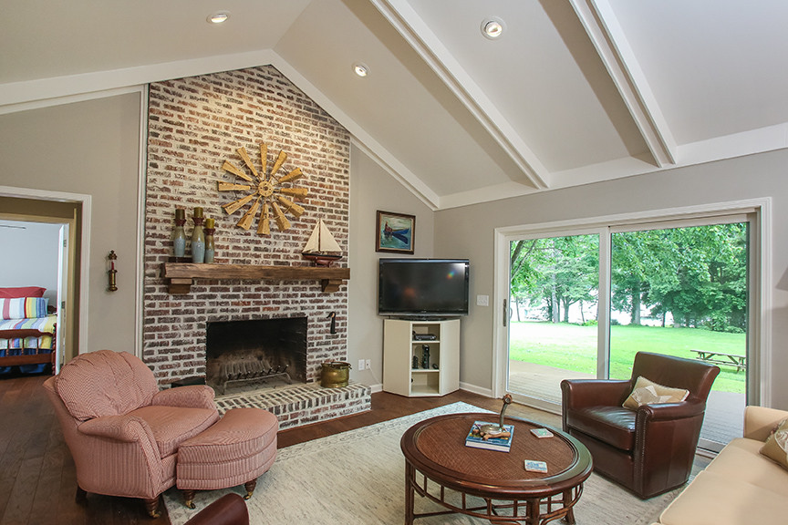 Example of a mid-sized classic formal and open concept medium tone wood floor living room design in Atlanta with gray walls, a standard fireplace, a brick fireplace and a tv stand