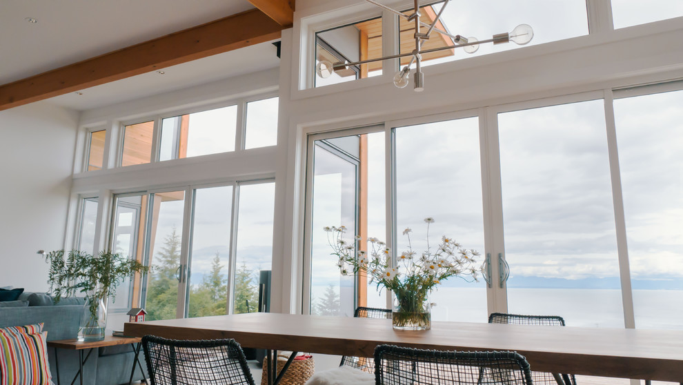 Mittelgroßes, Offenes Wohnzimmer mit weißer Wandfarbe, braunem Holzboden, Kamin und Kaminumrandung aus Beton in Vancouver
