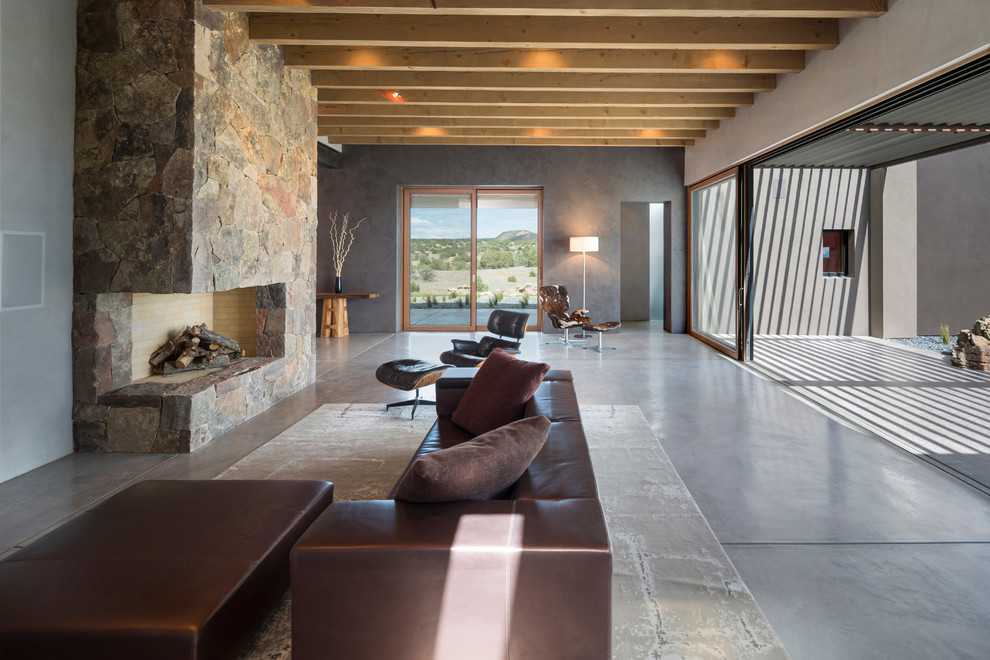 Inspiration pour un grand salon design ouvert avec un mur gris, sol en béton ciré, une cheminée standard, un manteau de cheminée en pierre, une salle de réception et aucun téléviseur.