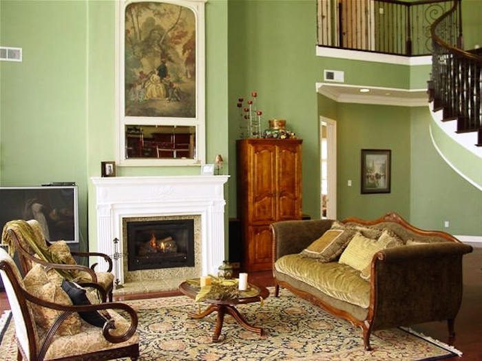 Immagine di un grande soggiorno minimal aperto con sala formale, pareti verdi, parquet scuro, camino classico, cornice del camino in legno e TV autoportante