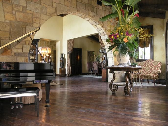 Großes, Fernseherloses, Offenes Mediterranes Musikzimmer ohne Kamin mit gelber Wandfarbe, dunklem Holzboden und braunem Boden in Austin
