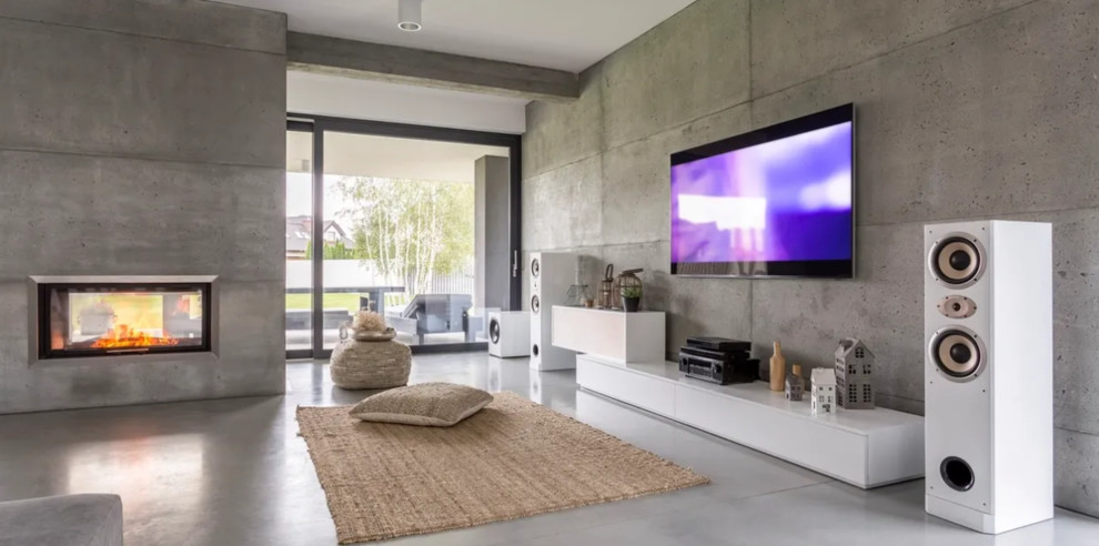 Источник вдохновения для домашнего уюта: большая открытая гостиная комната в современном стиле с серыми стенами, бетонным полом, двусторонним камином, фасадом камина из бетона, телевизором на стене и серым полом