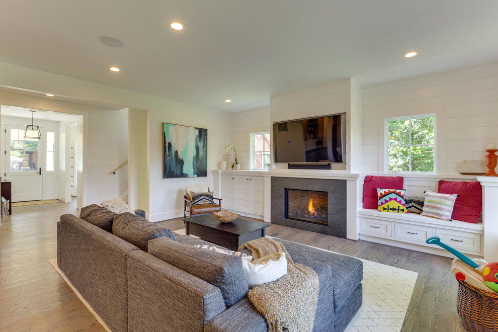 Large arts and crafts open concept medium tone wood floor living room photo in DC Metro with white walls, a standard fireplace, a wall-mounted tv and a tile fireplace