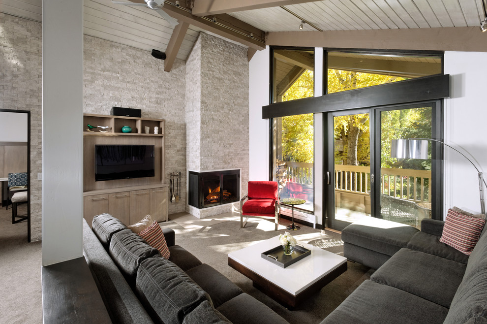Inspiration for a large contemporary formal and open concept carpeted and gray floor living room remodel in Denver with white walls, a corner fireplace, a stone fireplace and a wall-mounted tv