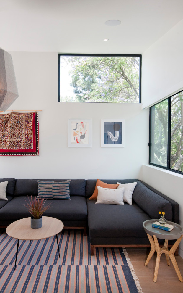 Großes Modernes Wohnzimmer im Loft-Stil mit weißer Wandfarbe, braunem Holzboden, Kamin, verputzter Kaminumrandung, braunem Boden und gewölbter Decke in Los Angeles