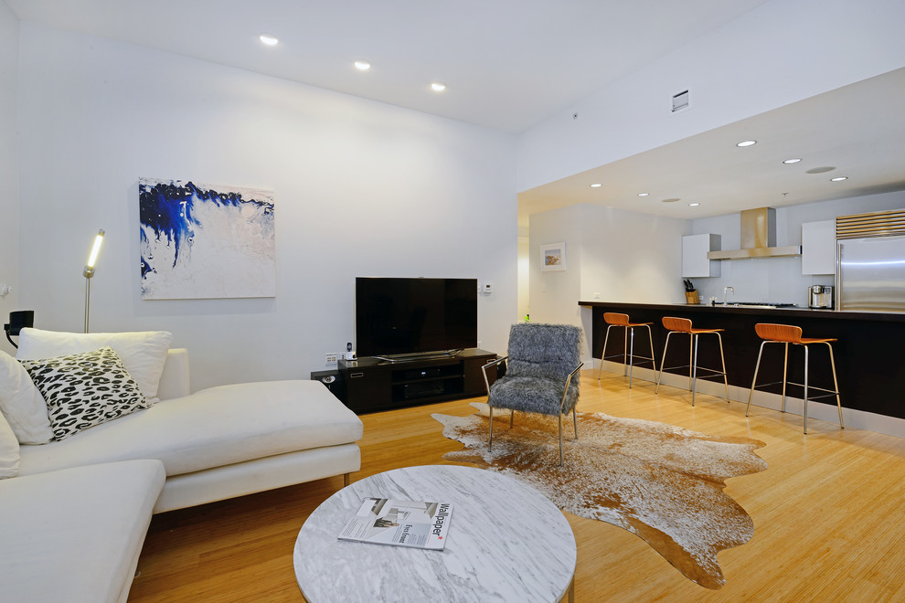 Immagine di un soggiorno contemporaneo con pareti bianche, pavimento in legno massello medio, nessun camino e TV autoportante