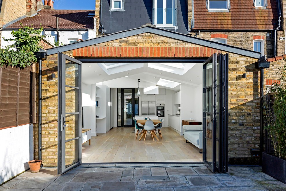 Offenes Modernes Wohnzimmer mit weißer Wandfarbe, hellem Holzboden, freistehendem TV und beigem Boden in London