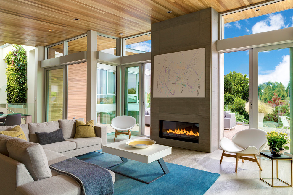 Photo of a large contemporary open plan living room in Seattle with white walls, medium hardwood flooring, a standard fireplace, a tiled fireplace surround and a concealed tv.
