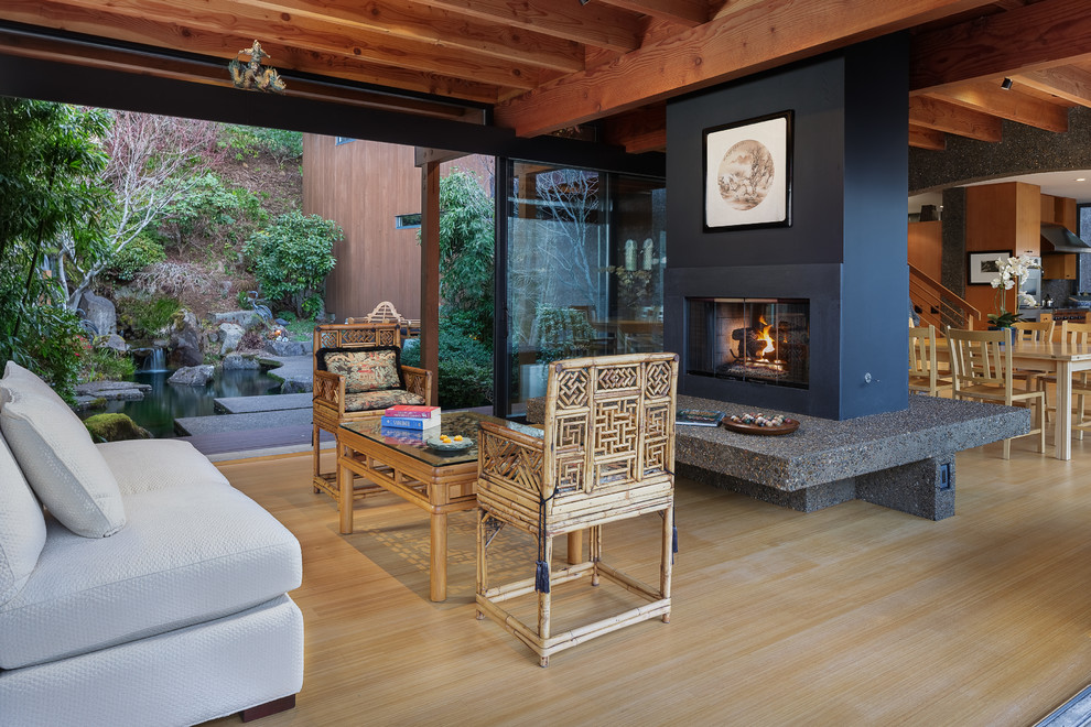 Foto de salón abierto de estilo zen grande sin televisor con suelo de bambú, chimenea de doble cara, marco de chimenea de hormigón y suelo beige