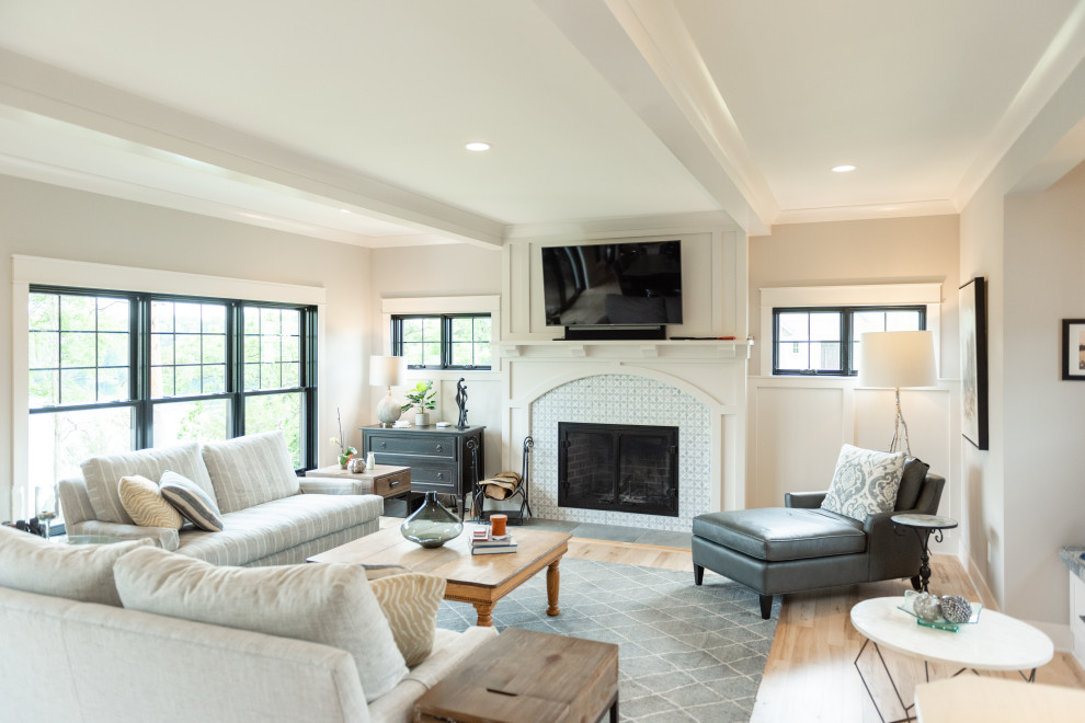 Transitional light wood floor, beige floor and exposed beam living room photo in Milwaukee with beige walls, a standard fireplace, a tile fireplace and a wall-mounted tv