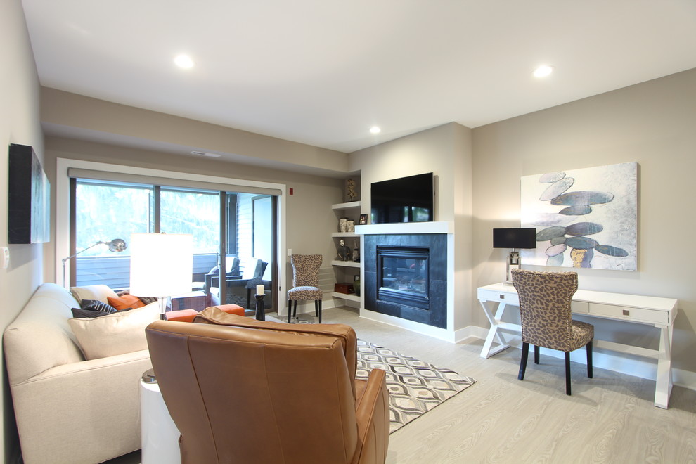 Пример оригинального дизайна: маленькая открытая гостиная комната в стиле модернизм с серыми стенами, полом из ламината, стандартным камином, фасадом камина из плитки и телевизором на стене для на участке и в саду