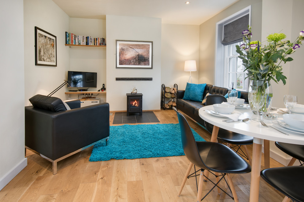 Mittelgroßes, Offenes Modernes Wohnzimmer mit beiger Wandfarbe, hellem Holzboden, Kaminofen und freistehendem TV in Sonstige