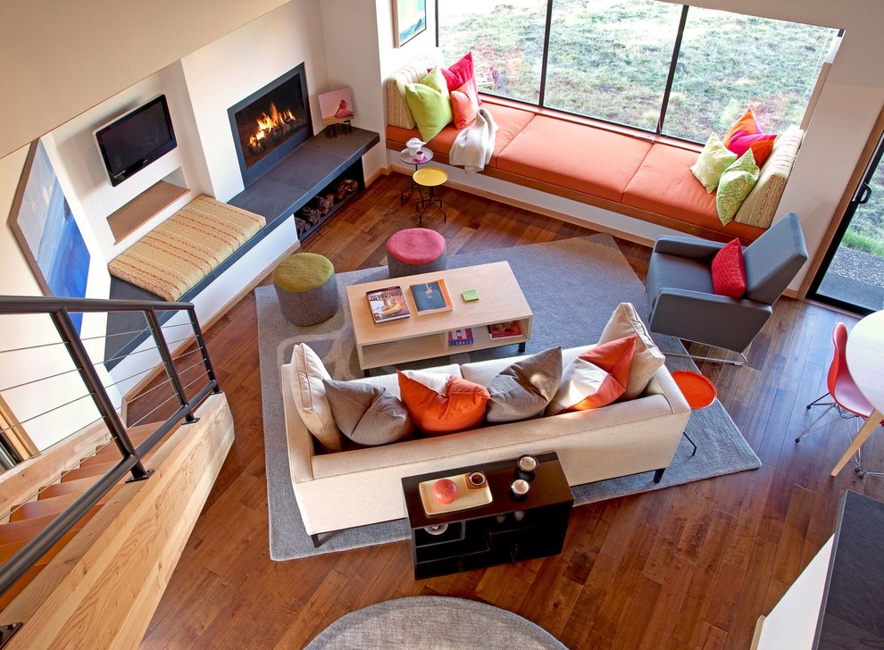 Offenes Stilmix Wohnzimmer mit beiger Wandfarbe, braunem Holzboden, Kamin, TV-Wand und orangem Boden in San Francisco