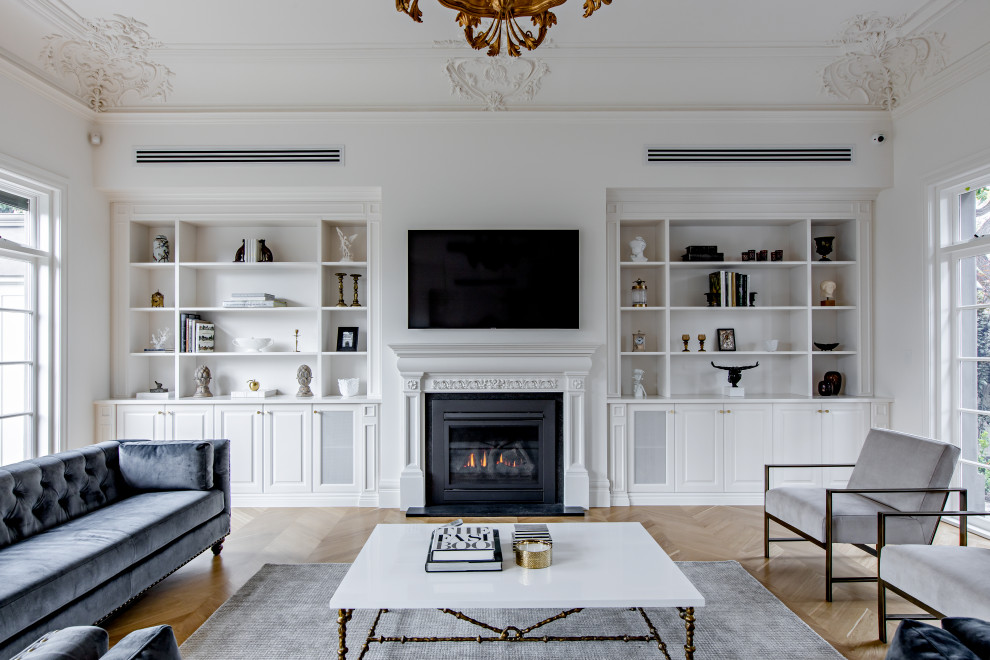 This is an example of a classic formal open plan living room in Adelaide with white walls, medium hardwood flooring, a standard fireplace, a plastered fireplace surround and a wall mounted tv.