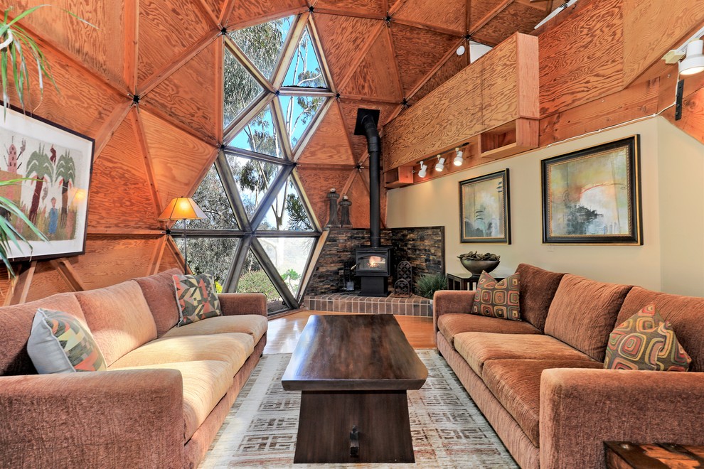 Stilmix Wohnzimmer mit beiger Wandfarbe, braunem Holzboden, Kaminofen und braunem Boden in San Diego