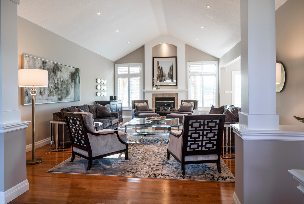 This is an example of a large contemporary open plan living room in Toronto with grey walls, medium hardwood flooring, a standard fireplace, a plastered fireplace surround and a concealed tv.
