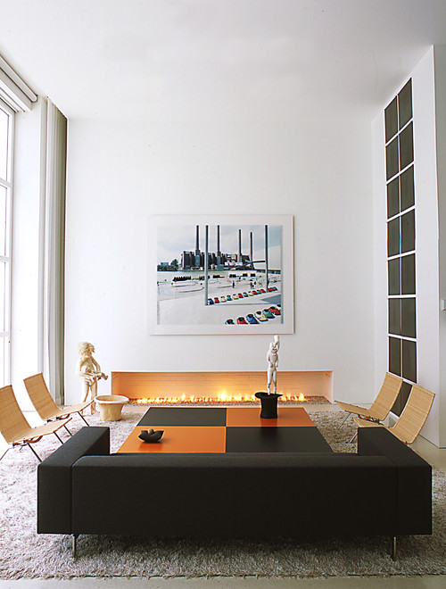 The seating area occupies a portion of the living room and gallery space. The orientation of the couch helps to separate this area of the living room - gallery. A low, minimalist gas fireplace adds warmth and becomes the focal point of the seating area.
Example of a trendy living room design in DC Metro with white walls and a ribbon fireplace 