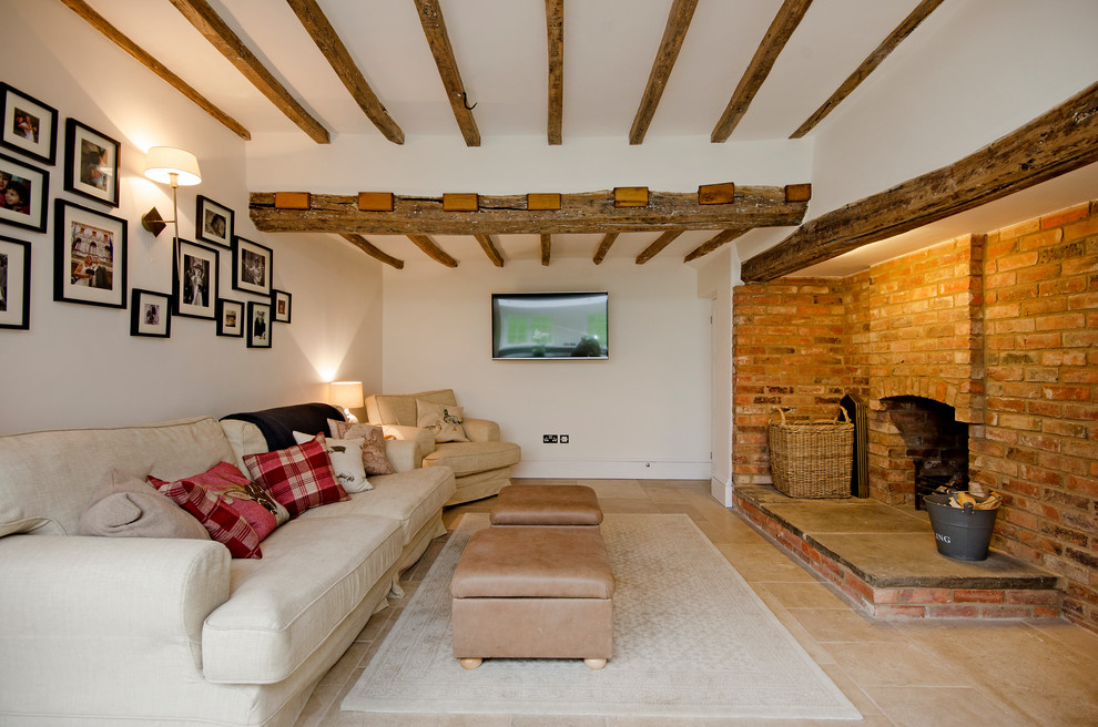 Пример оригинального дизайна: гостиная комната в стиле кантри с белыми стенами, стандартным камином, фасадом камина из кирпича и телевизором на стене